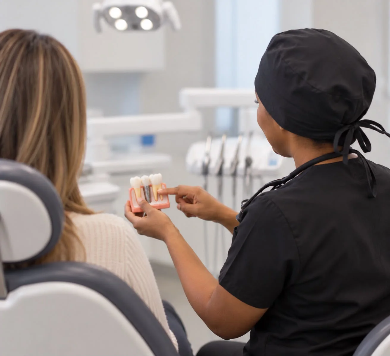 Dr Nyaradzo Mutezo showing a patient a dental implant model Dr Nyaradzo Mutezo showing a patient a dental implant model